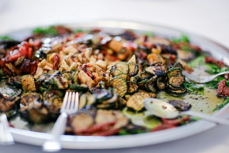 A platter of grilled vegetables with herbs and nuts.